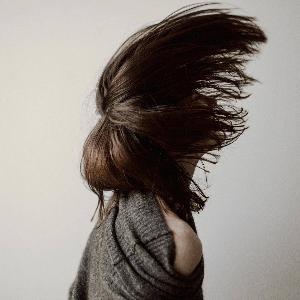 woman in gray sweater standing near white wall